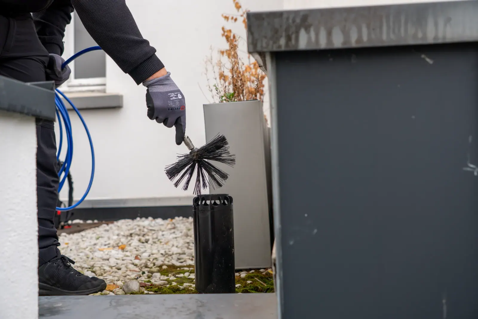 Schornsteinfeger bei der Arbeit mit Kehrbesen auf dem Dach